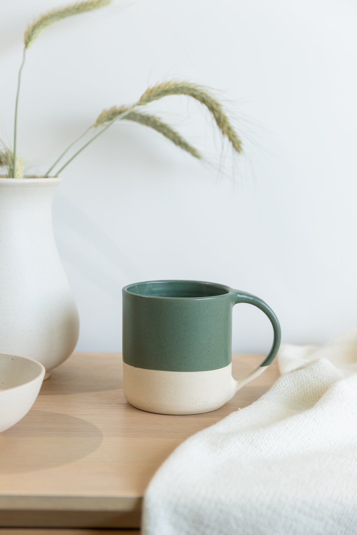 Green mug on a wooden surface with neutral background