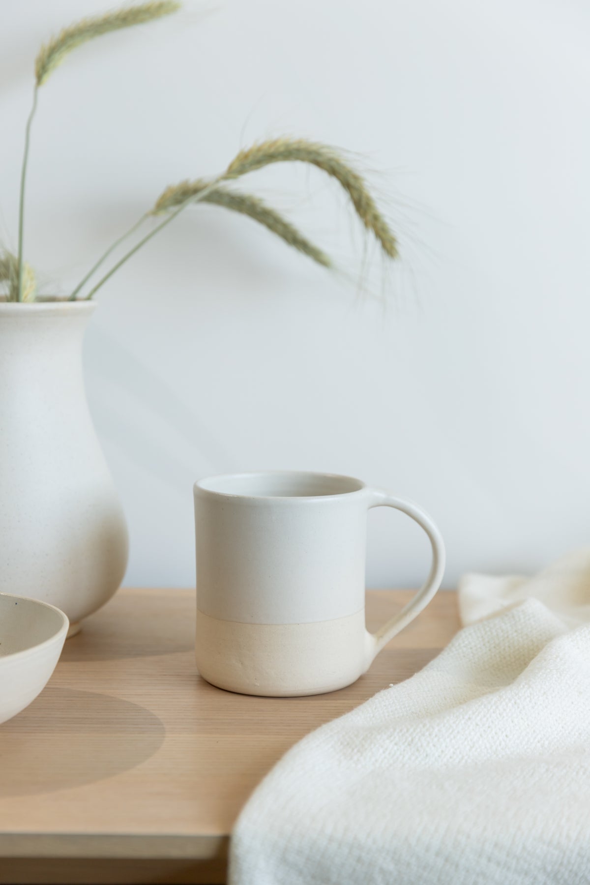 White ceramic mug on a wooden surface with a neutral background
