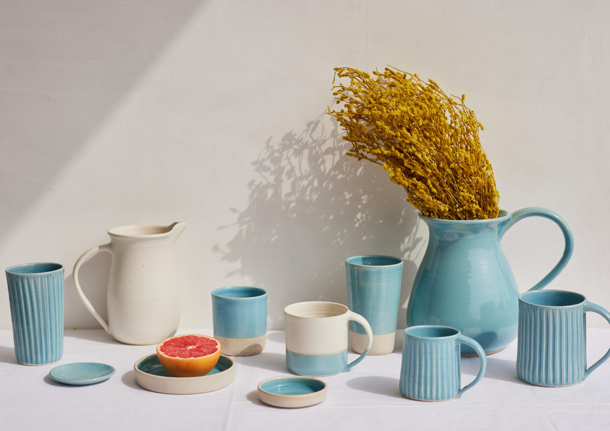 Collection of ceramic mugs, jugs, and a pitcher on a white surface with a light gray background.